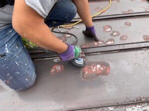 屋根の既存塗膜を電動工具を使用してケレンしています。