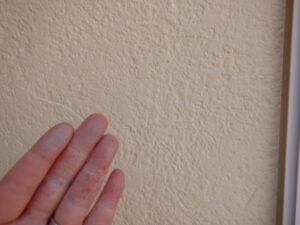 外壁を触った手に白い粉が付着している。